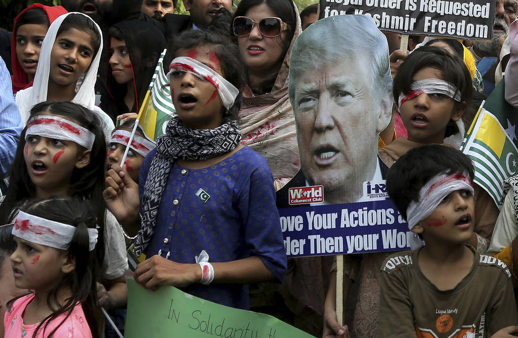 Pakistan children dress up like injured Kashmiri children and hold a portrait of U.S. President ...