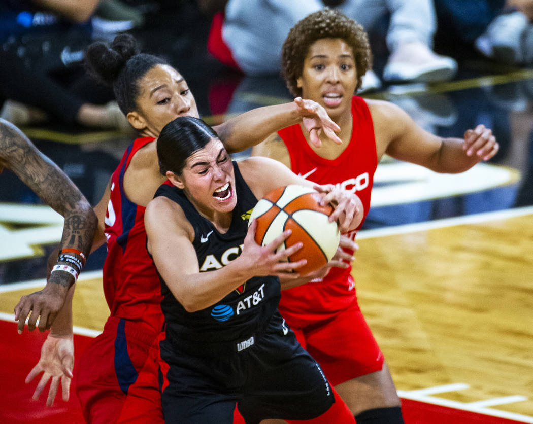 Las Vegas Aces guard Kelsey Plum (10, center) secures a loose ball over Washington Mystics forw ...