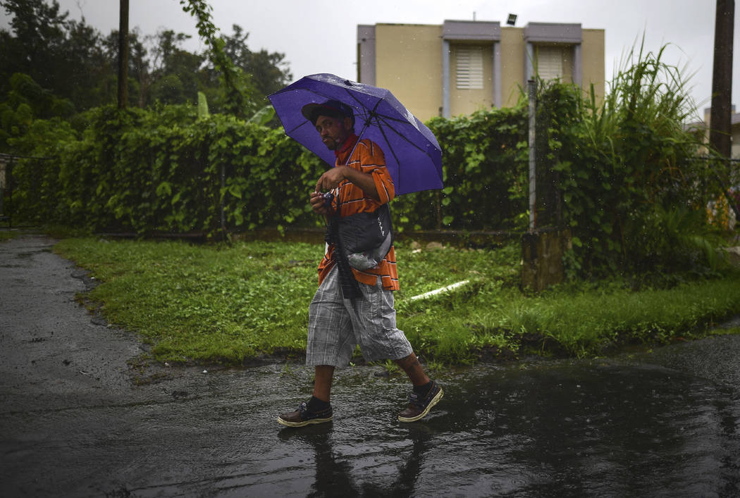A man walks in the rain in Yabucoa, before the arrival of Tropical Storm Karen, in Yabucoa, Pue ...