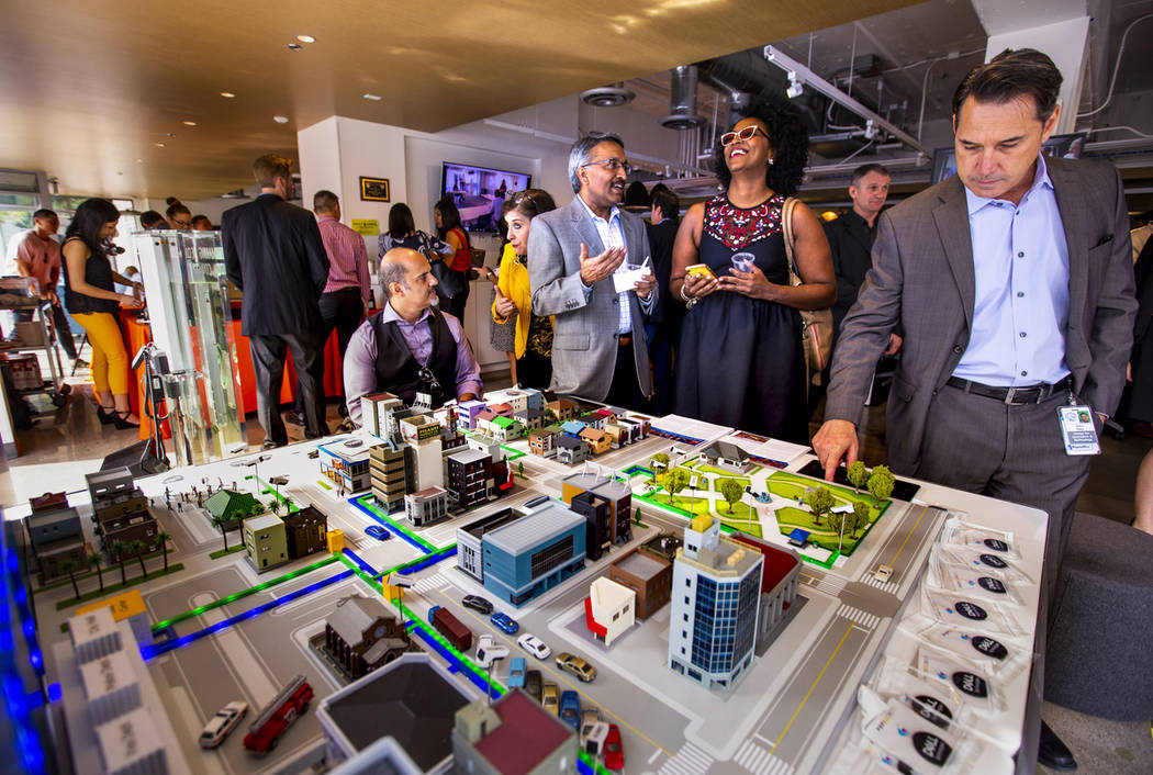 Attendees talk about the uses of an NTT Smart City Platform demonstrated on a model during the ...