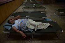 Luz Aponte Velazquez lies on a cot at the Ramon Quinones Medina High School, one of the shelter ...