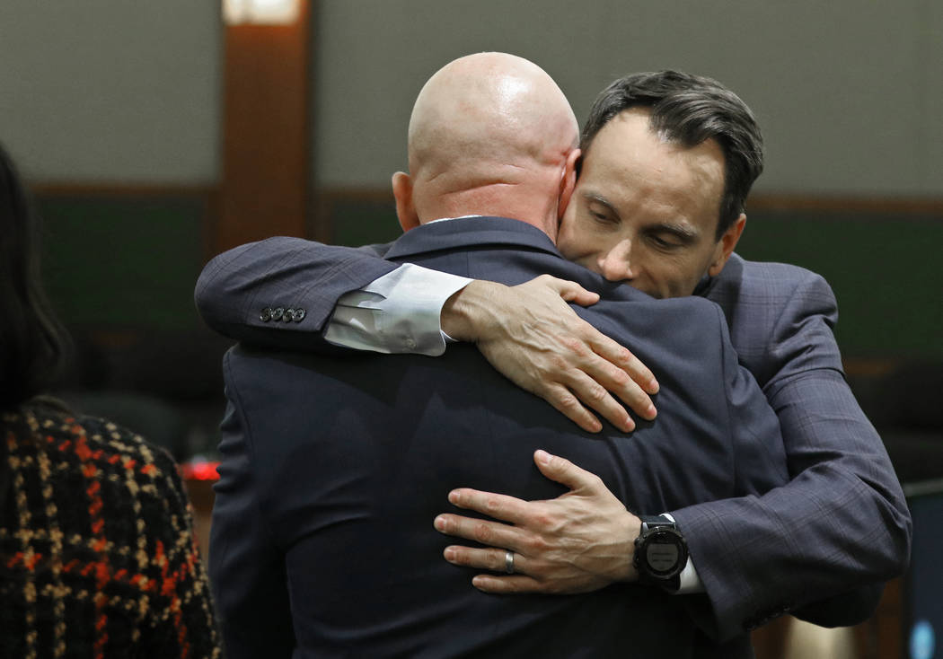 Defense attorney Josh Tomsheck, facing, hugs Las Vegas police Lt. James "Tom" Melton, ...