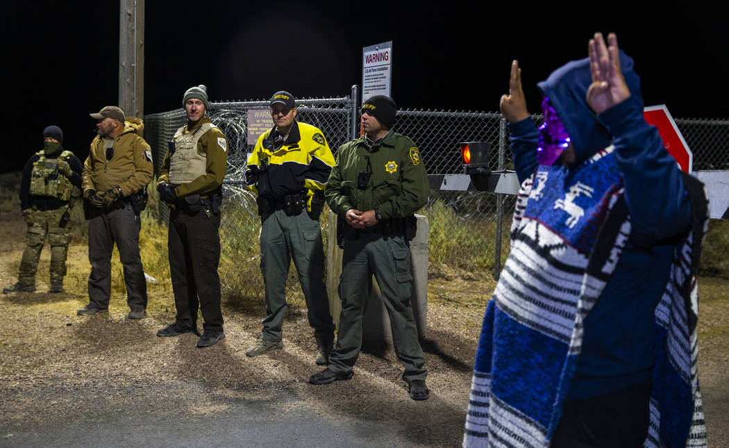 A costumed man stands near security personnel outside the back gate of Area 51 in homage to the ...