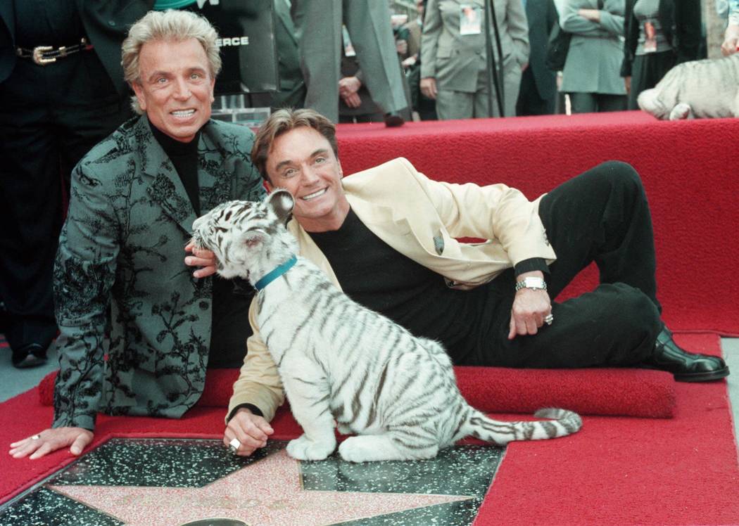 Illusionists Siegfried Fischbacher, left and Roy Horn with a white tiger cub after they unveile ...