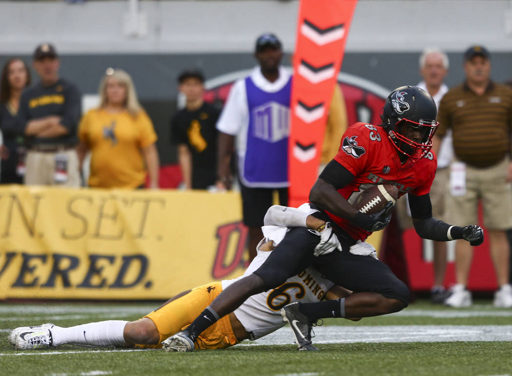 UNLV wide receiver Devonte Boyd (83) is tackled by Wyoming defensive back Marcus Epps (6) durin ...
