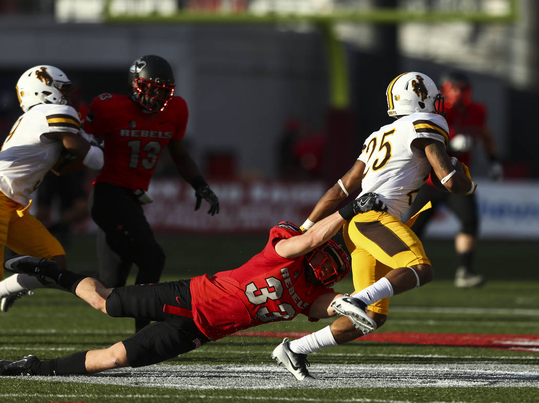 UNLV defensive back Dalton Baker (33) takes down Wyoming wide receiver Austin Conway (25) durin ...