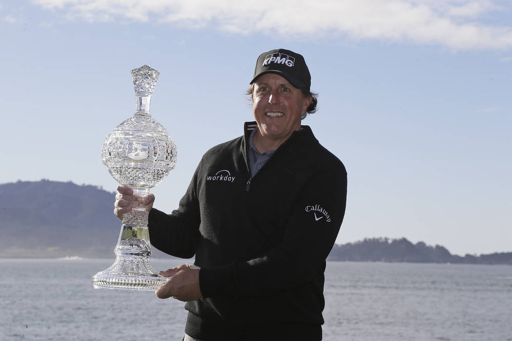 Phil Mickelson poses with his trophy on the 18th green of the Pebble Beach Golf Links after win ...