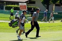 Phil Mickelson walks with his caddie and brother, Tim Mickelson, up to the second green of the ...