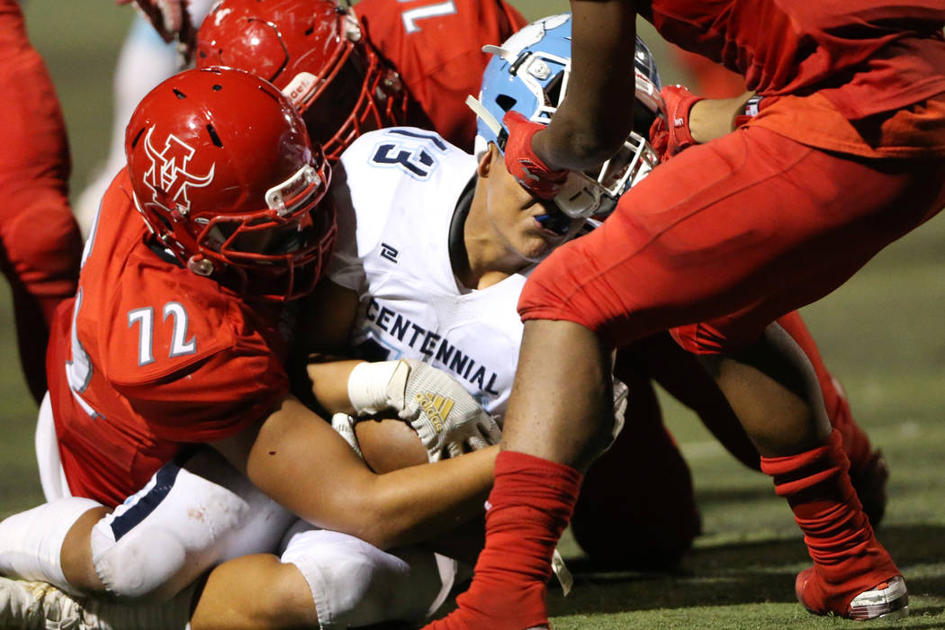 Arbor View's Jaedyn Jackson (11) rips the helmet from Centennial's Ronaven Mokiao (13) for a pe ...