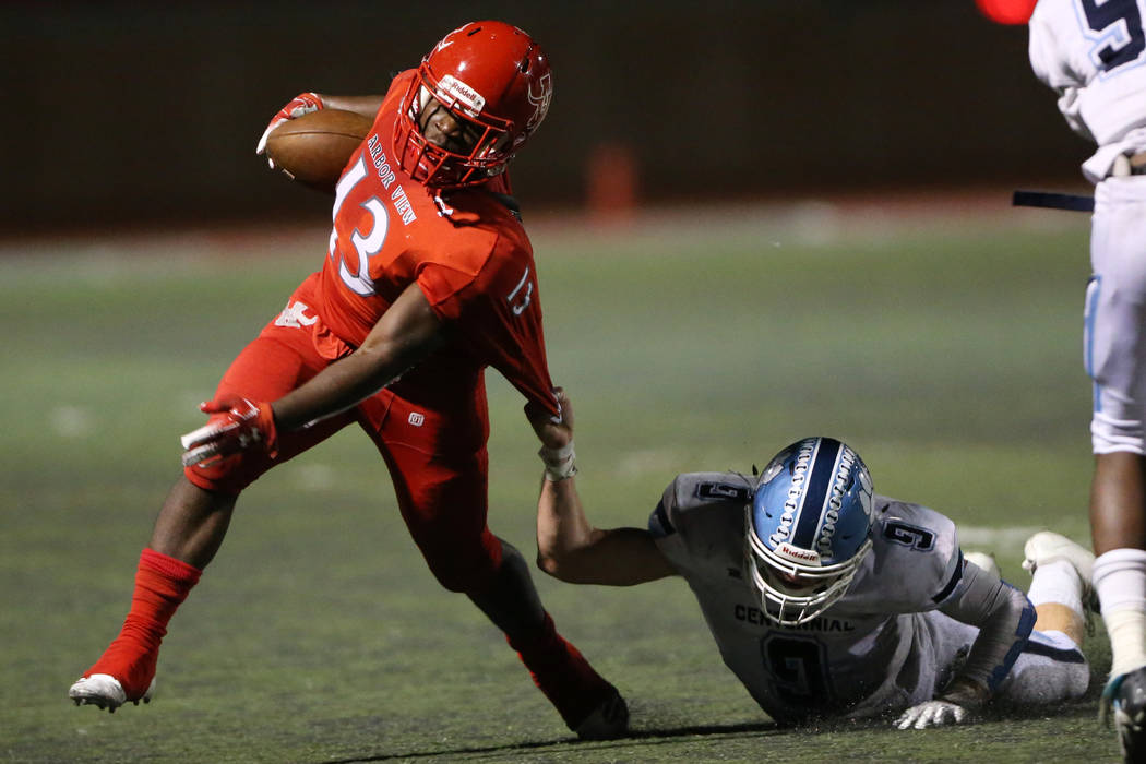 Arbor View's D'Andre Washington (13) deflects a tackle from Centennial's Nate Conger (9) during ...