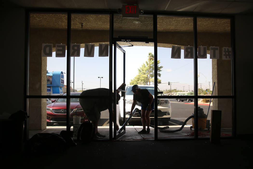 Volunteers Richard MacLean, left, and Diana Gomez, clean up shattered glass after a break-in to ...
