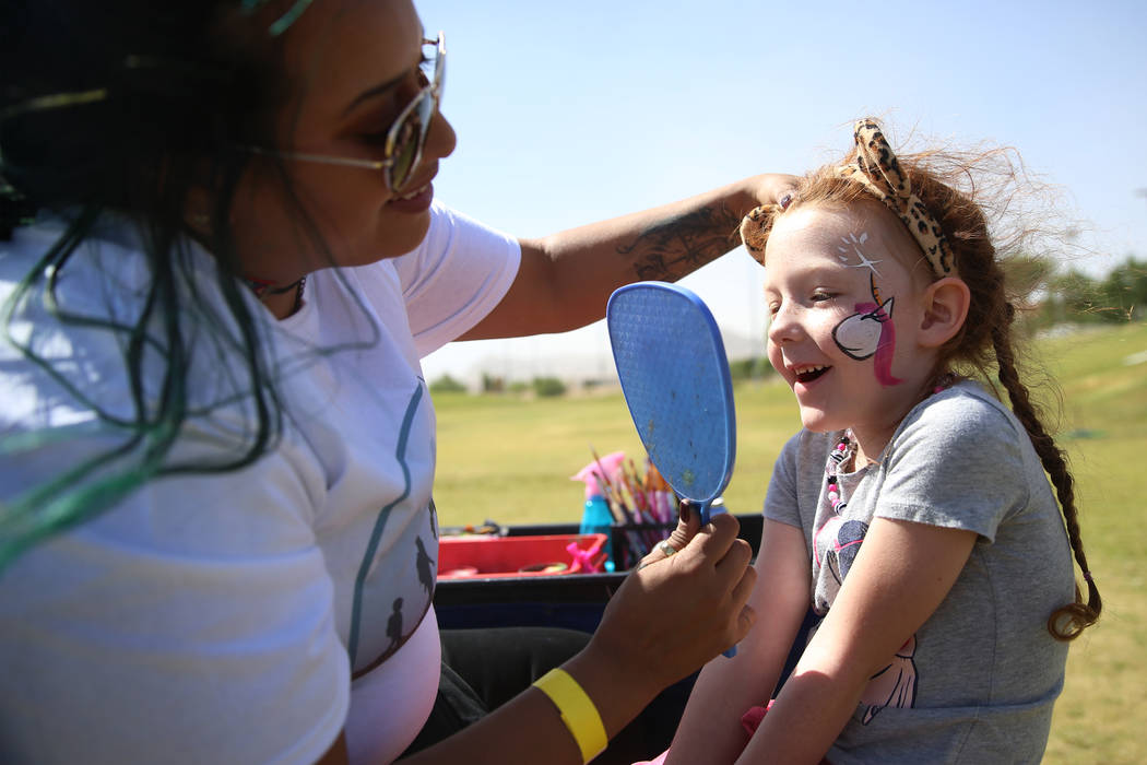 Adelaide Satterwhite, 6, looks at the face painting by Christian Ramos, during a celebration of ...