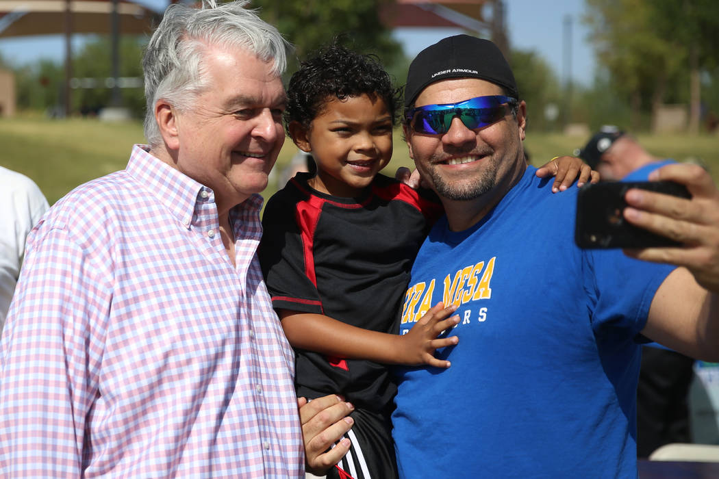 Gov. Steve Sisolak, left, takes a photo with Eric Cummings and his son, Gage, 6, of Las Vegas, ...