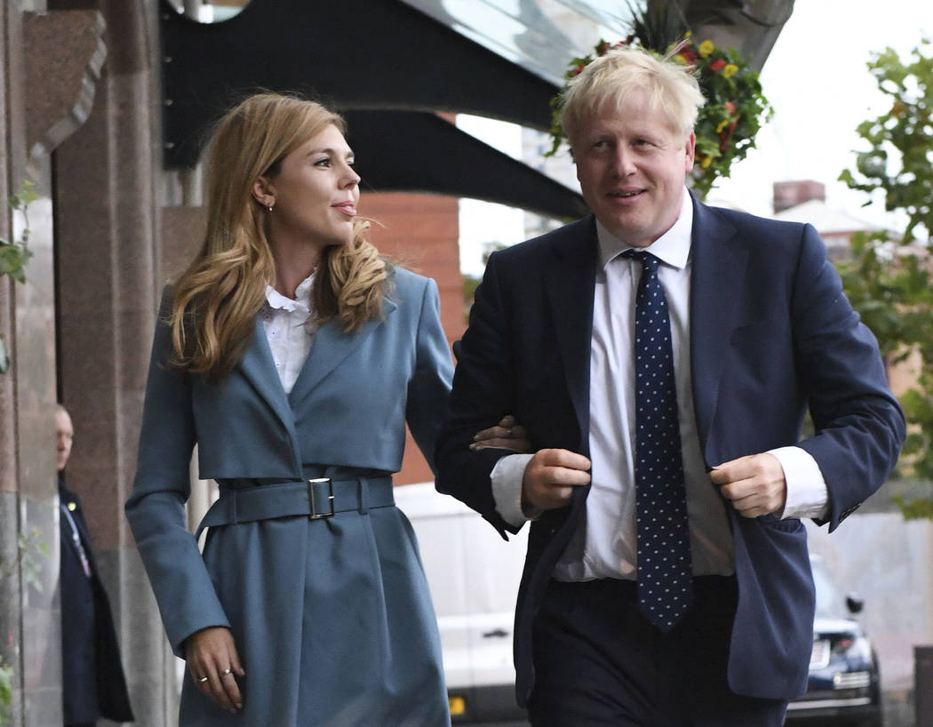 Britain's Prime Minister Boris Johnson arrives, accompanied by partner Carrie Symonds, ahead of ...