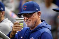 Chicago Cubs manager Joe Maddon salutes a fan from the dugout before a baseball game against th ...