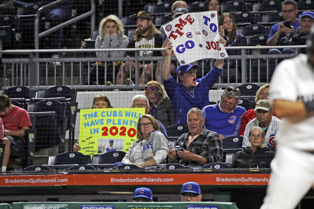 A Chicago Cubs fan holds a sign as Cubs manager Joe Maddon, bottom right, stands in the dugout ...