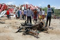 Somalis watch the wreckage of the car bomb after an attack on a European Union military convoy ...