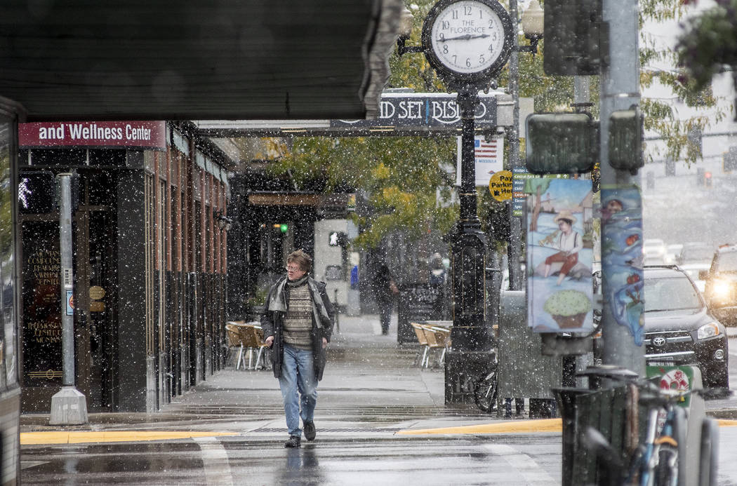 A pedestrian crosses Front Street under snowfall in Missoula, Mont., Sunday, Sept. 29, 2019. Mo ...