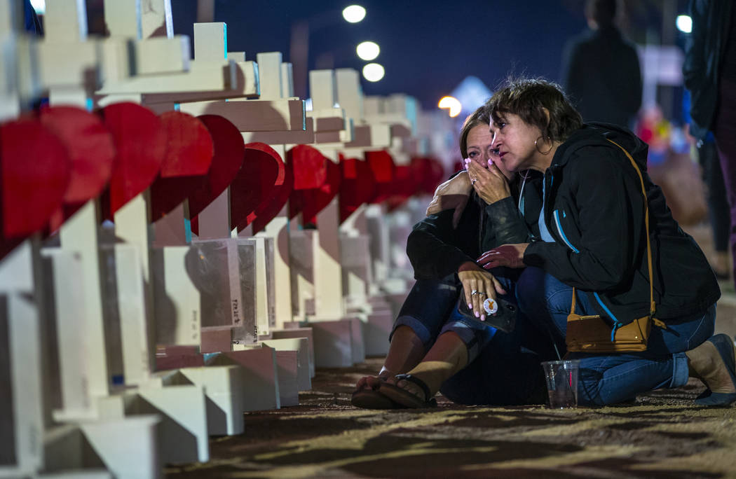 Sharon Hoover, left, and Antoinette Romero hug by where Greg Zanis has placed 58 crosses near t ...