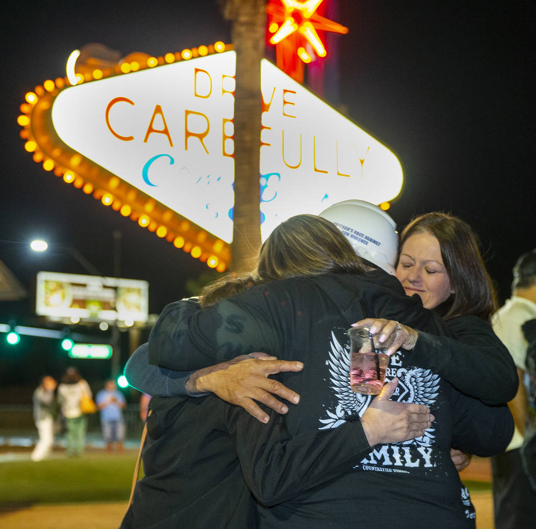 Greg Zanis, hard hat, is hugged by Sharon Hoover, right, and others after placing 58 crosses ne ...