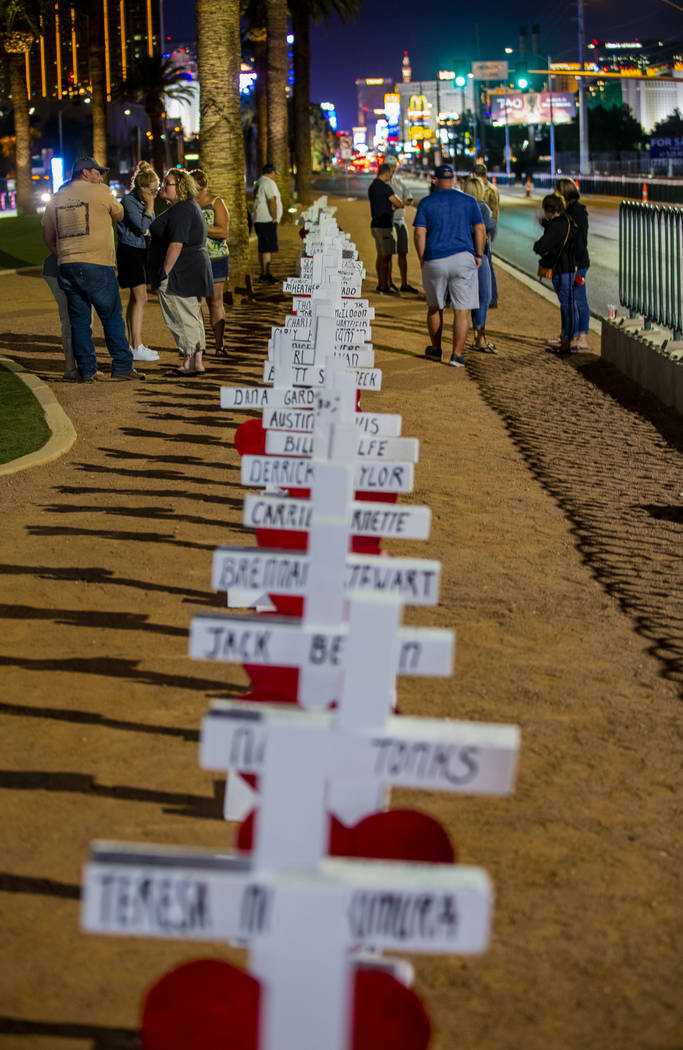 Visitors walk along the line of 58 crosses Greg Zanis placed near the "Welcome to Fabulous Las ...