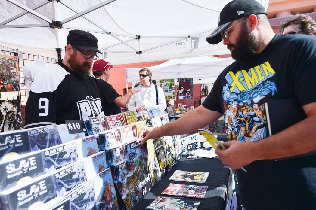 Heath Randall, 39, right, buys a comic book from writer Greg Boucher, left, at the tent for the ...