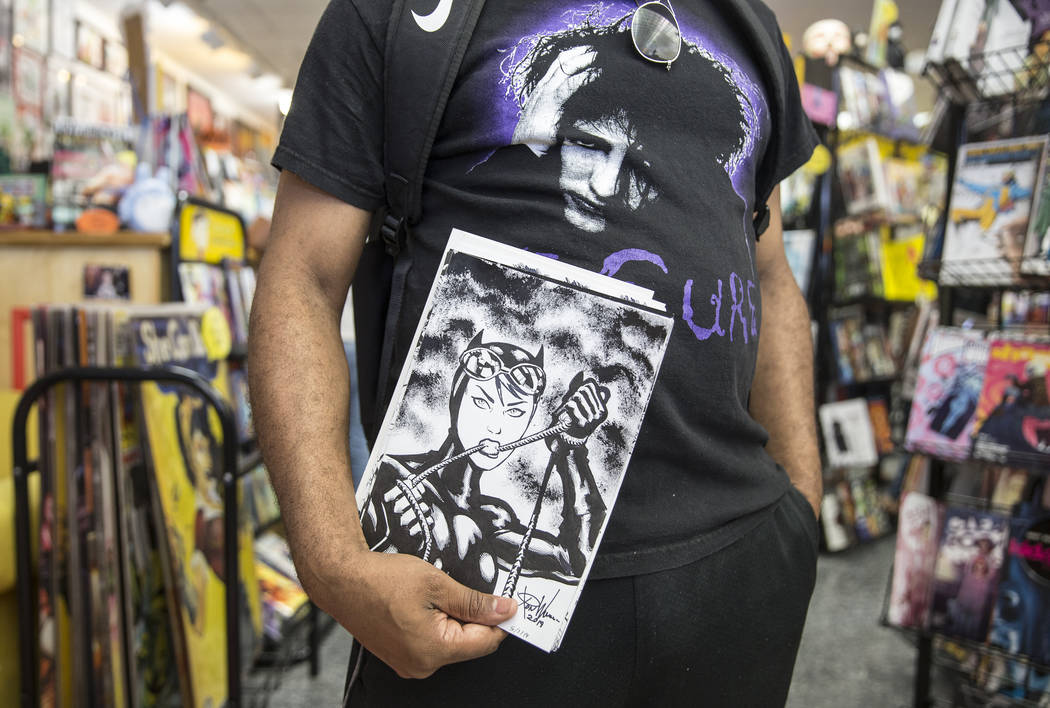 Comic book illustrator Ron Williams holds a sketch of Catwoman during free comic book day at Al ...