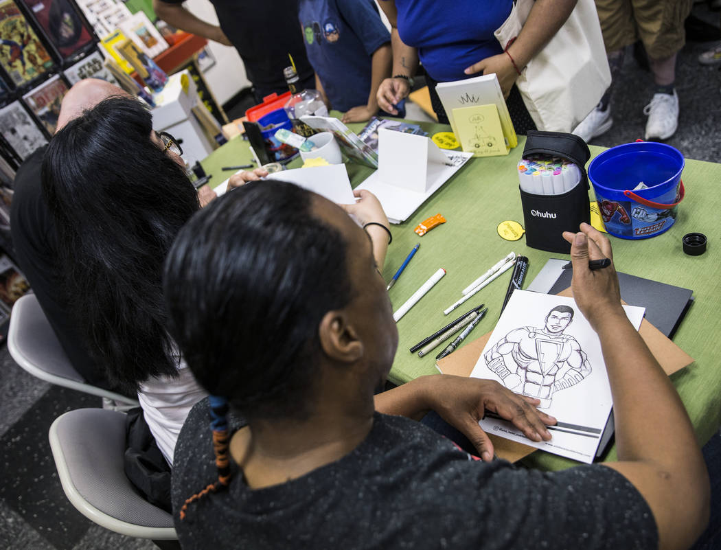 Comic book illustrator Ed Nesmith, right, draws a sketch of Shazam! during free comic book day ...