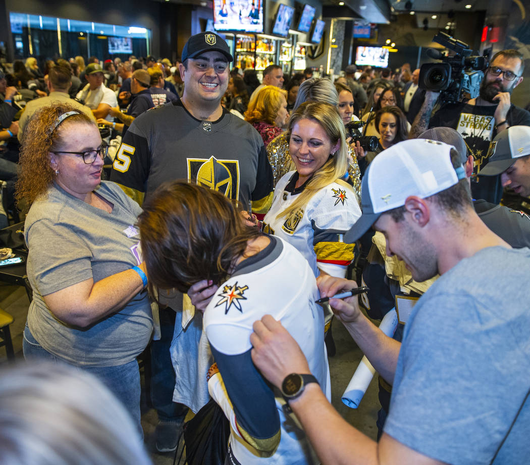 The Vegas Golden Knights Brayden McNabb, right, signs an autograph during a meet and greet to h ...