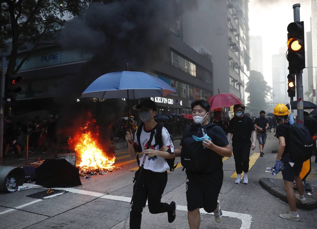 People run as police use tear gas to disperse anti-government protesters in Hong Kong, Tuesday, ...