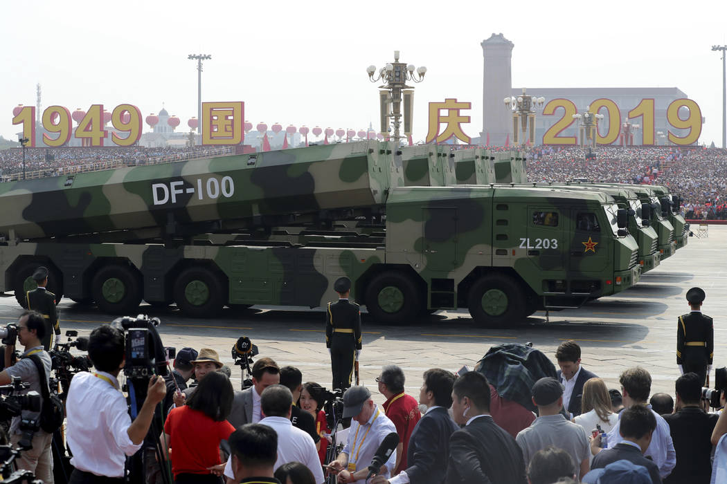 Military vehicles carrying DF-100 roll down as members of a Chinese military honor guard march ...