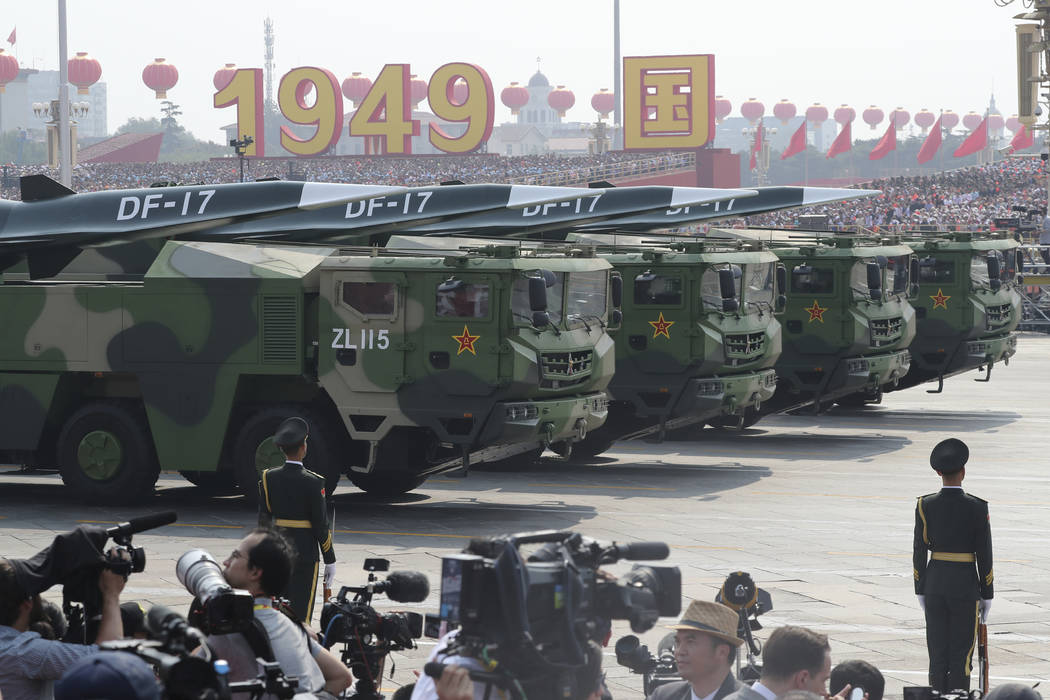 Military vehicles, carrying DF-17, roll down as members of a Chinese military honor guard march ...