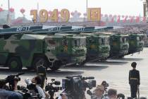 Military vehicles, carrying DF-17, roll down as members of a Chinese military honor guard march ...