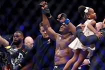 Kamaru Usman, right, raises his hand in victory against Tyron Woodley in the welterweight title ...