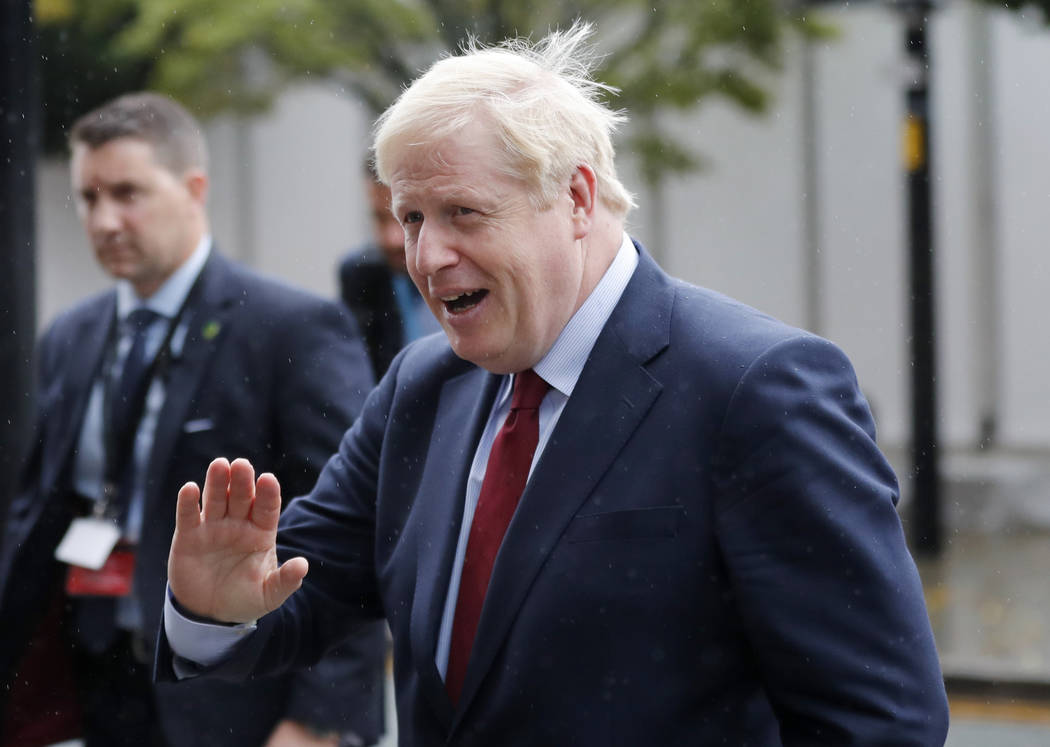 Britain's Prime Minister Boris Johnson rushes through the rain during the Conservative Party Co ...