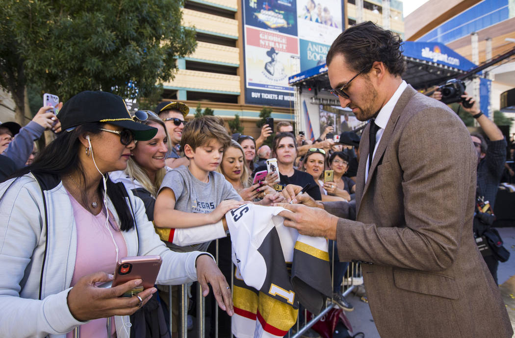 Golden Knights' Mark Stone signs autographs on the gold carpet after arriving for the NHL seaso ...