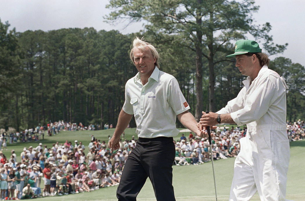 Greg Norman of Australia hands his club to his caddy on number two green after he made birdie d ...