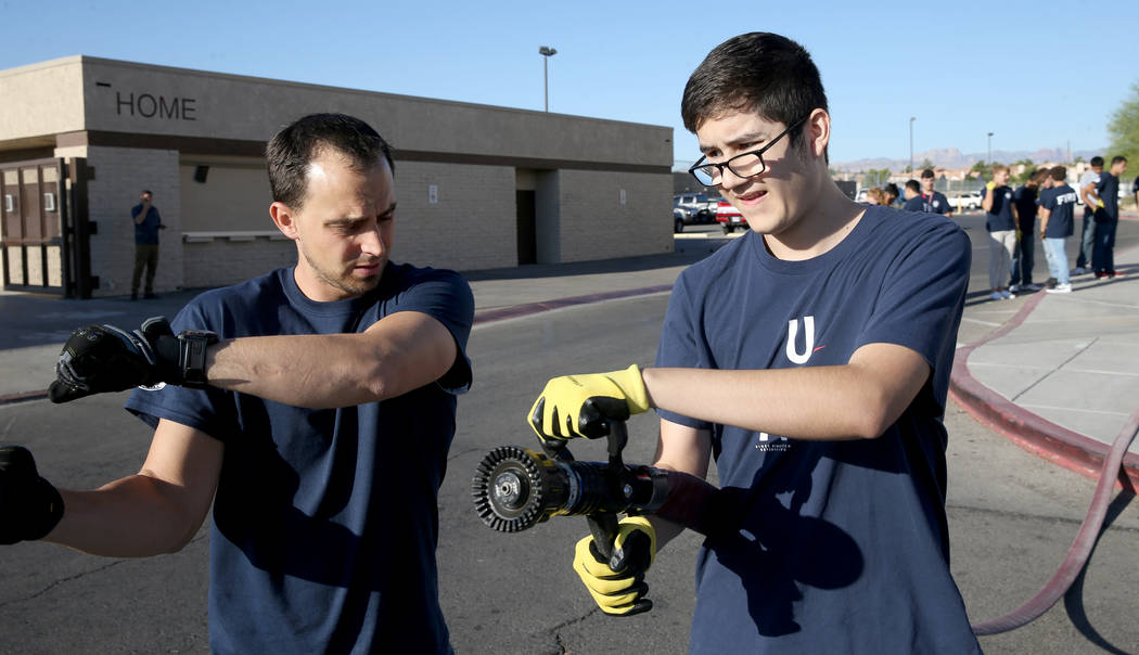 Bonanza High School Fire Science Academy teacher Chris Batterman shows junior Josh Silva how to ...