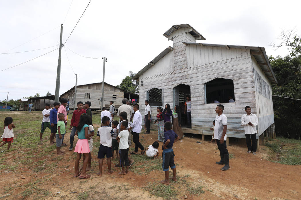 Residents gather outside the Catholic church of Novo Cruzador, Brazil, after attending a prayer ...