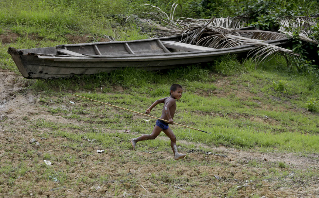 A boy runs through the indigenous Tikuna village of Santa Rosa, Brazil, Saturday, Sept. 21, 201 ...