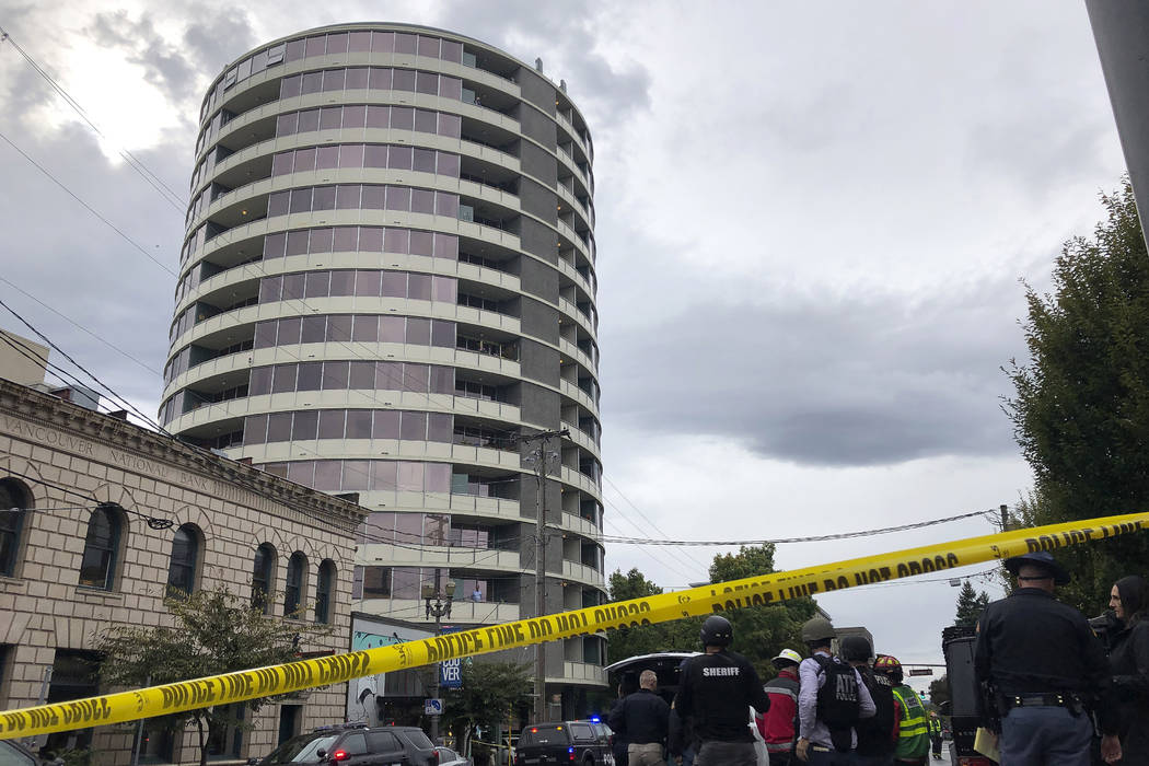 Police respond to a shooting at an apartment building, top rear, in Vancouver, Wash., Thursday, ...