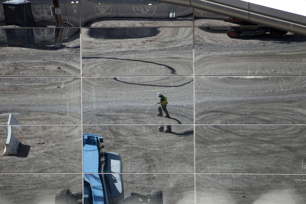 A construction reflects on glass installed at the Raiders Allegiant Stadium in Las Vegas, Thur ...