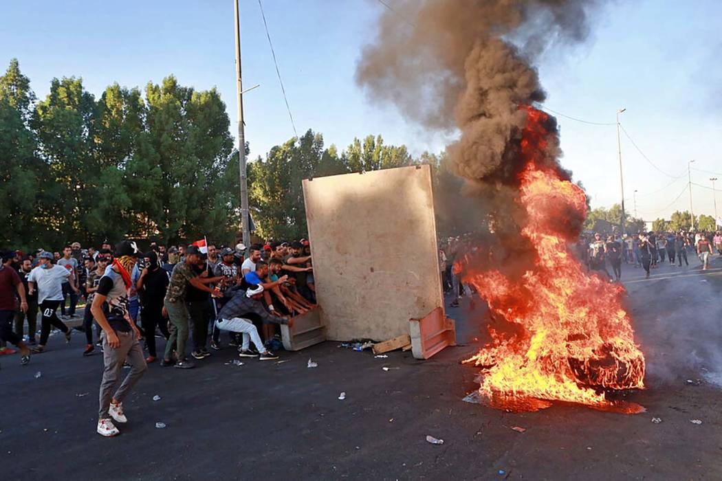 Anti-government protesters set fires and close a street during a demonstration in Baghdad, Iraq ...
