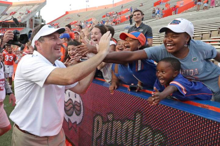 Florida head coach Dan Mullen high fives fans as he leaves the field after defeating Towson in ...