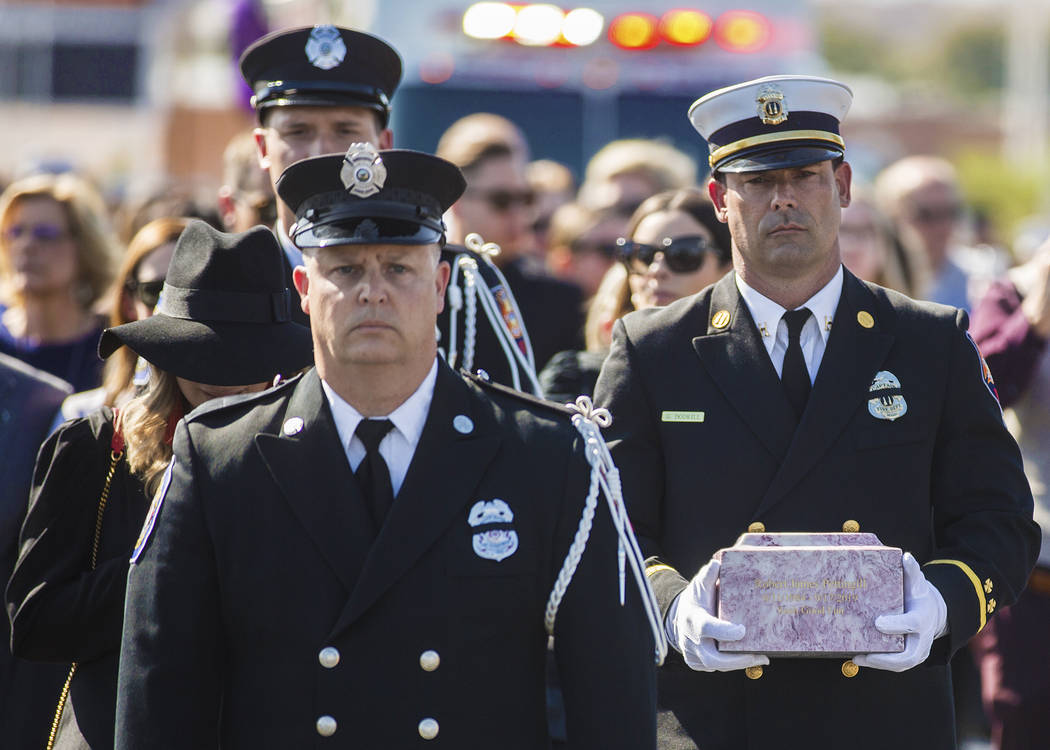 Henderson Fire Captain Garrett Dodrill, right, holds the urn containing the cremated remains of ...