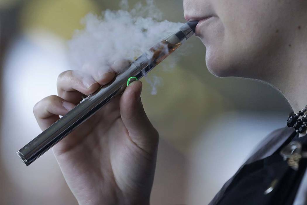 In this Friday, Oct. 4, 2019 photo, a woman using an electronic cigarette exhales in Mayfield H ...