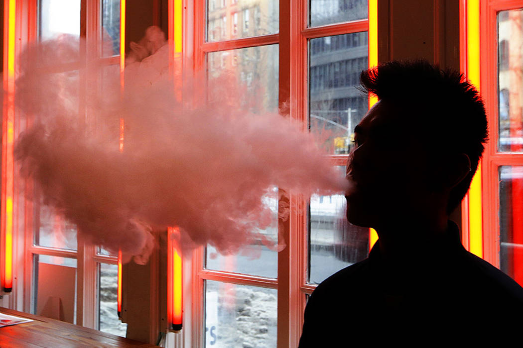 FILE - In this Feb. 20, 2014, file photo, a patron exhales vapor from an e-cigarette at a store ...
