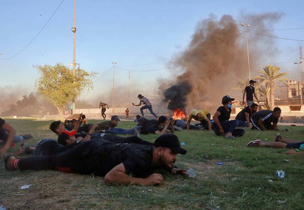 Anti-government protesters take cover while Iraq security forces fire during a demonstration in ...