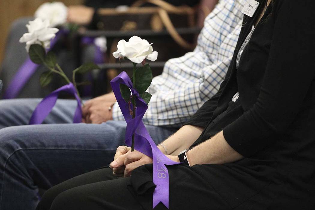 People hold flowers with the names of domestic violence victims killed in the last year during ...