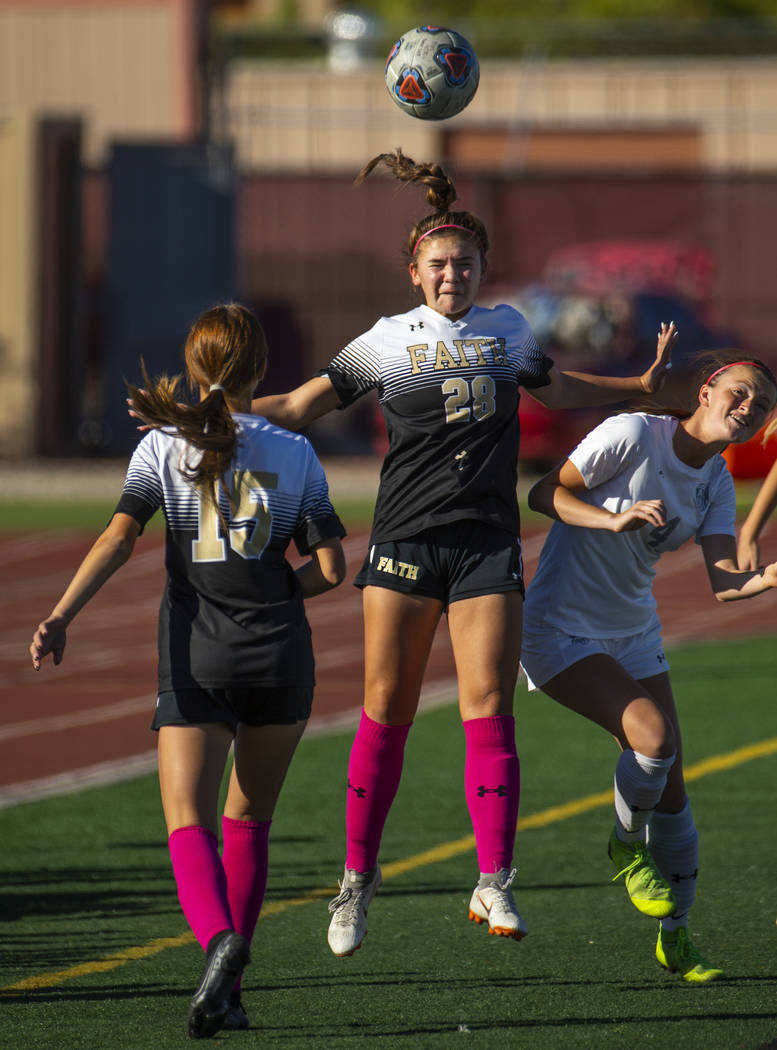 Faith Lutheran's Tatum Bowers (28, center) heads the ball away from Arbor View's Makayla Farnum ...